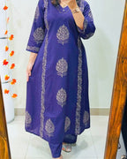 Person wearing a purple dress with white floral patterns in front of a mirror.