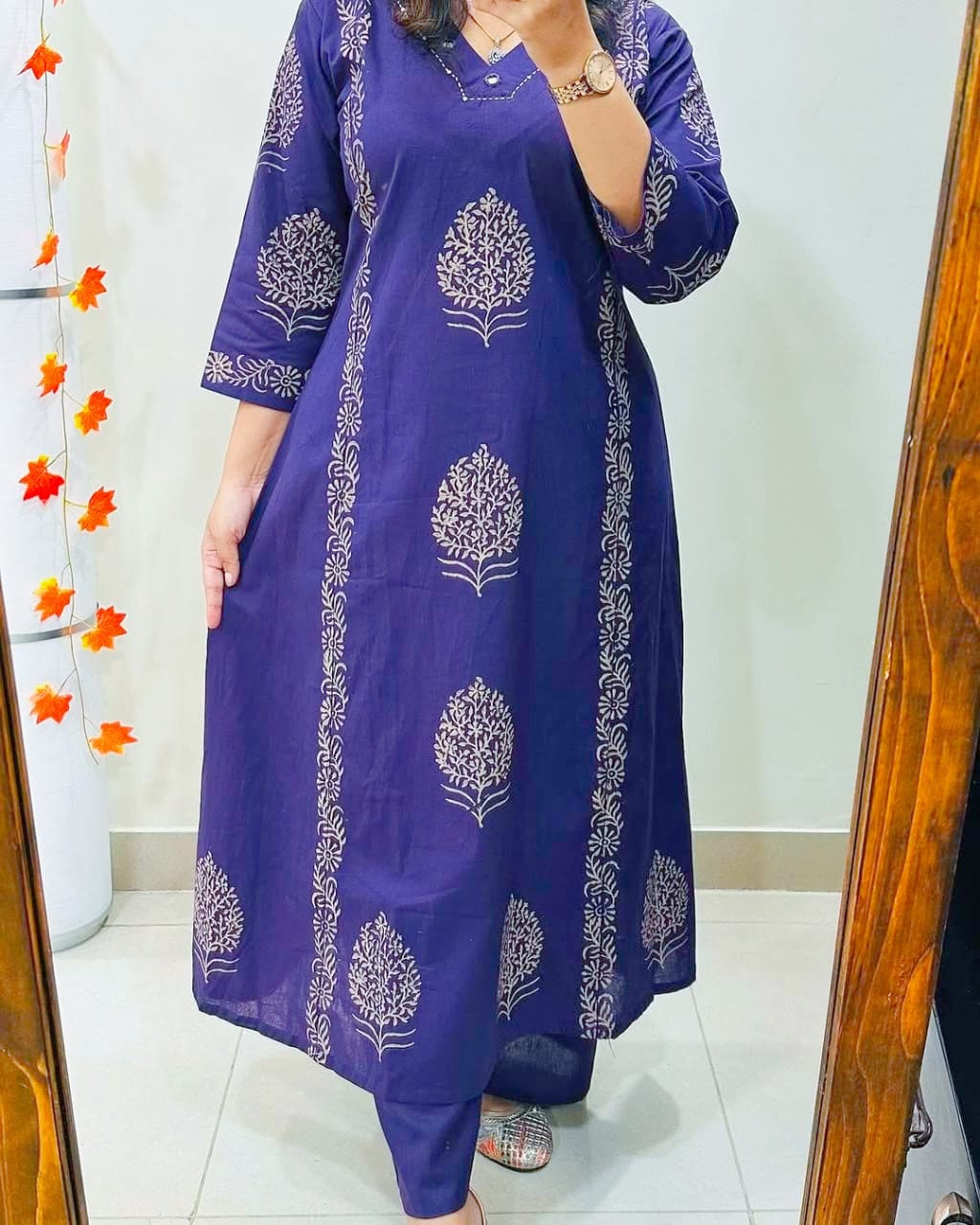 Person wearing a purple dress with white floral patterns in front of a mirror.